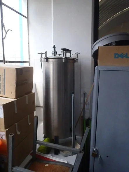 AUTOCLAVE MOSTRANDO VALVULA DE SEGURIDAD Y MANMETRO, INSTALADA EN UN LUGAR DESORDENADO